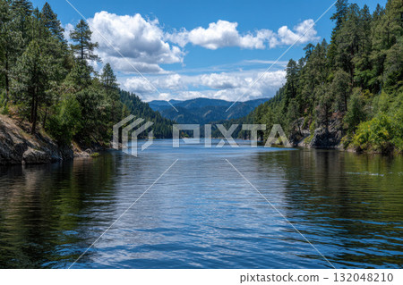 Serene lake framed by mountains and trees 132048210
