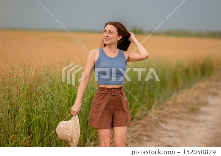 Woman enjoying a summer day on a rural path surrounded by golden fields 132050829