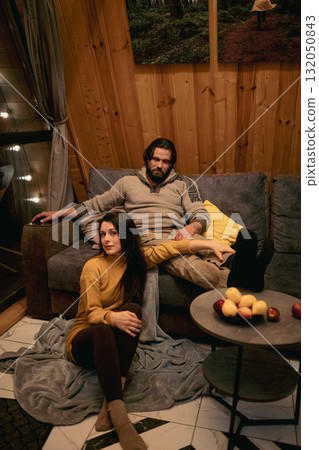Couple relaxing indoors in a cozy wooden cabin during a quiet evening Couple relaxing indoors in a cozy wooden cabin during a quiet evening 132050843