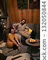 Cozy evening at home with a couple relaxing on a couch in a wooden cabin setting 132050844