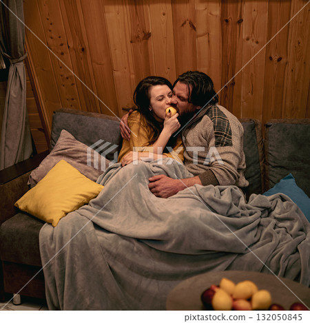 Cozy indoor evening with couple sharing a playful moment on the couch 132050845