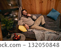 Relaxing man enjoys cozy indoor space with snacks and warm decor during evening at home 132050848