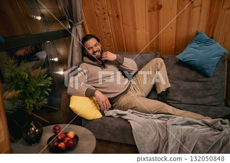 Relaxing man enjoys cozy indoor space with snacks and warm decor during evening at home Relaxing man enjoys cozy indoor space with snacks and warm decor during evening at home 132050848