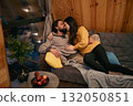 Couple enjoying a cozy moment together on a sofa in a wooden cabin 132050851