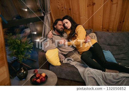 Cozy evening on the couch with a couple enjoying each other's company in a wooden cabin 132050852