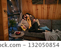 Cozy couple shares a warm moment on a sofa in a wooden cabin during winter evening 132050854