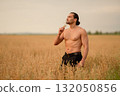 Farmer examines wheat and oats in a golden field during late afternoon 132050856