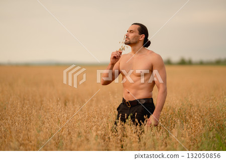 Farmer examines wheat and oats in a golden field during late afternoon 132050856