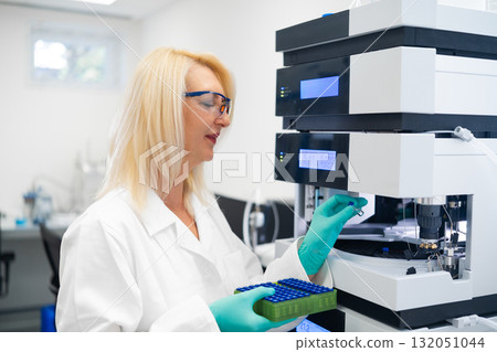 Professional female scientist using HPLC instrument for pharmaceutical and biochemical sample testing. Modern chromatography methods and advanced laboratory analysis. 132051044