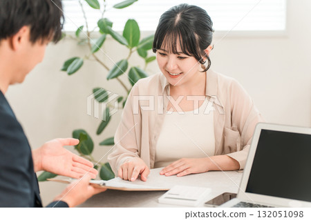 A businessman presenting a price using a calculator during a business meeting and a female customer listening to him A businessman presenting a price using a calculator during a business meeting and a female customer listening to him 132051098