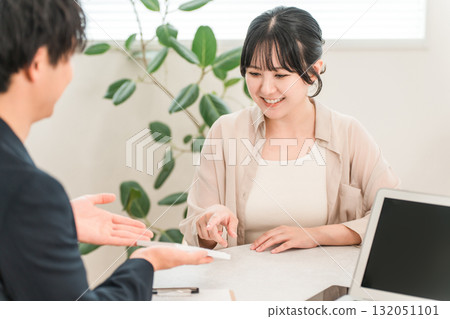 A businessman presenting a price using a calculator during a business meeting and a female customer listening to him A businessman presenting a price using a calculator during a business meeting and a female customer listening to him 132051101