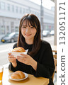 A young woman eating bread at a cafe 132051171