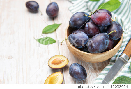 Fresh plums in wooden bowl with knife Fresh plums in wooden bowl with knife 132052024