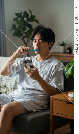 早安.坐在沙發上，一邊刷牙一邊看手機。 132052173