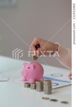 Financial Empowerment. Saving coins in a pink piggy bank for future goals. 132052868