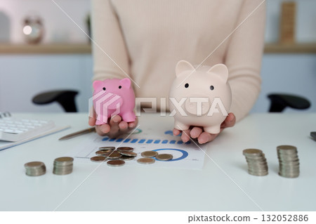 Financial Management. Woman comparing piggy banks and coins, illustrating savings strategies. Financial Management. Woman comparing piggy banks and coins, illustrating savings strategies. 132052886