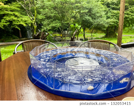 Nagashi somen. A machine that rotates somen noodles in water. A typical summer sight in Japan. Nagashi somen. A machine that rotates somen noodles in water. A typical summer sight in Japan. 132053415