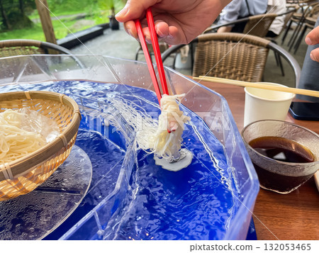 Nagashi somen in Japan. The act of putting somen noodles into circulating water. A typical summer scene. Nagashi somen in Japan. The act of putting somen noodles into circulating water. A typical summer scene. 132053465