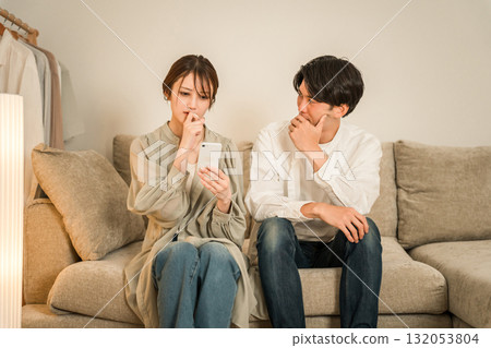 一對夫婦在沙發上看智慧型手機時感到震驚和驚訝 132053804