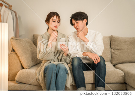 一對夫婦在沙發上看智慧型手機時感到震驚和驚訝 132053805