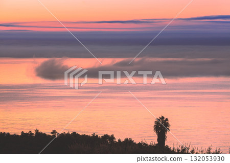 Seascape at sunset. Minimalist landscape. Palm tree silhouette against the sea. Clouds descending over the sea. Nerja, Spain, Europe Seascape at sunset. Minimalist landscape. Palm tree silhouette against the sea. Clouds descending over the sea. Nerja, Spain, Europe 132053930