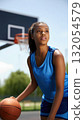 African American teen girl in blue sportswear with a basketball on the court outdoors, vertical image. 132054579