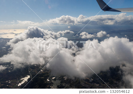Outside the airplane window, there are clear skies and white clouds 132054612