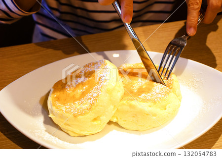 一位女士正在切割鬆軟的煎餅 132054783