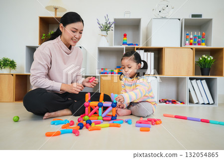 toddler girl and mother playing colorful magnetic construction toy at home 132054865