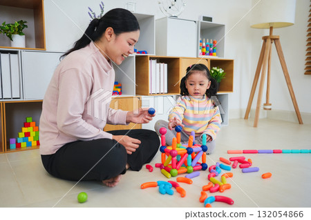 toddler girl and mother playing colorful magnetic construction toy at home 132054866