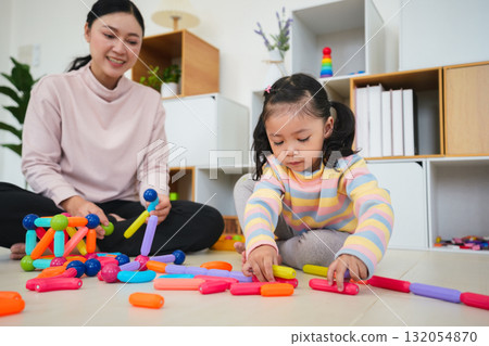 toddler girl and mother playing colorful magnetic construction toy at home 132054870