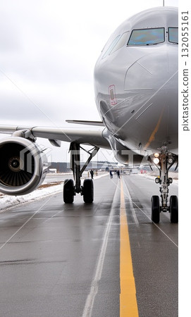 Two large white airplanes are parked closely on a snowy tarmac with trees in the background, showcasing a winter scene 132055161