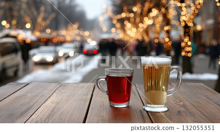 Two warm beverages sit on a wooden table, surrounded by holiday decor and cheerful visitors at a festive market scene 132055351