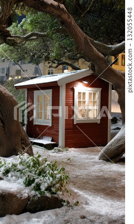A cozy wooden cabin stands beside a beautifully lit Christmas tree, glowing warmly under the night sky in a snowy landscape A cozy wooden cabin stands beside a beautifully lit Christmas tree, glowing warmly under the night sky in a snowy landscape 132055448