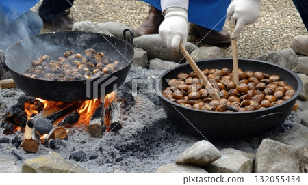 Chestnuts are being roasted over an open flame, creating a warm and inviting atmosphere among gathered people enjoying the activity Chestnuts are being roasted over an open flame, creating a warm and inviting atmosphere among gathered people enjoying the activity 132055454