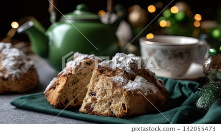 Delicious scones featuring dried fruit are served next to cozy cups of tea on a cheerful tablecloth, creating a warm atmosphere Delicious scones featuring dried fruit are served next to cozy cups of tea on a cheerful tablecloth, creating a warm atmosphere 132055473