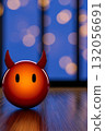 Cute devil figurine with a glowing orange finish placed on a wooden surface under soft blue lighting 132056691