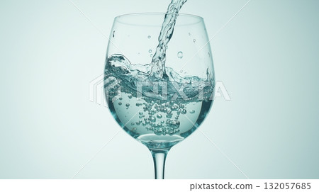 Close-up of water pouring into a glass with bubbles and splash 132057685