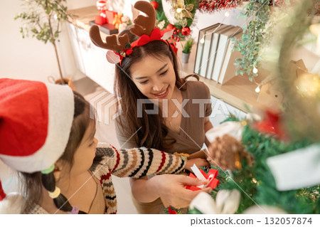 Family Christmas Bonding. Woman and child joyfully decorating a Christmas tree together. Family Christmas Bonding. Woman and child joyfully decorating a Christmas tree together. 132057874
