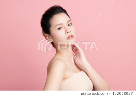 A beautiful young Asian woman with clean, fresh skin against a pink background. Skincare, facial treatment, cosmetology, beauty, and spa. An elegant portrait of an Asian woman. A beautiful young Asian woman with clean, fresh skin against a pink background. Skincare, facial treatment, cosmetology, beauty, and spa. An elegant portrait of an Asian woman. 132058037