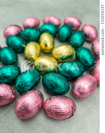 Chocolate easter eggs forming colorful spiral on grey background Chocolate easter eggs forming colorful spiral on grey background 132058147