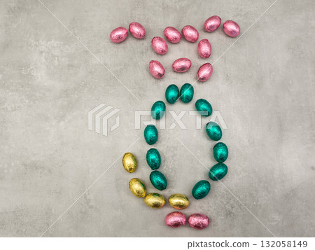 Chocolate easter eggs forming rabbit symbol on grey background copy space Chocolate easter eggs forming rabbit symbol on grey background copy space 132058149