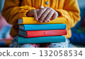 Child's hands holding colorful books. School and education illustration. 132058534
