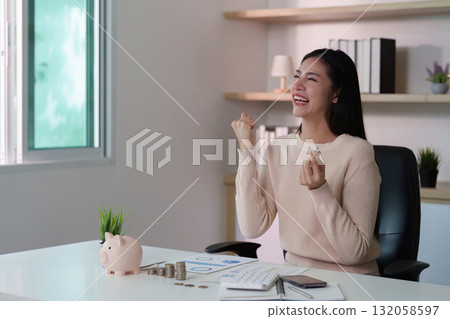 Financial Achievement. Happy woman celebrating financial success with coins and a piggy bank. Financial Achievement. Happy woman celebrating financial success with coins and a piggy bank. 132058597