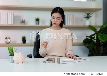 Financial analysis. A woman examining bills while managing her finances at a desk. Financial analysis. A woman examining bills while managing her finances at a desk. 132058603