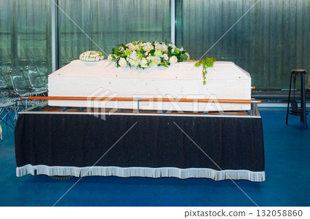 White Coffin With Floral Arrangements On Black Table For Funeral Ceremony And Mourning 132058860