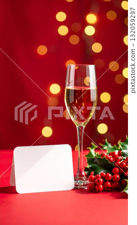 Champagne glass with blank card and holly berries on Christmas background with soft bokeh 132059297