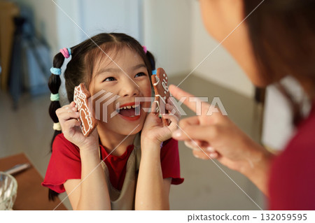 Gingerbread Delight. Child joyfully presenting decorated cookies during holiday baking. 132059595