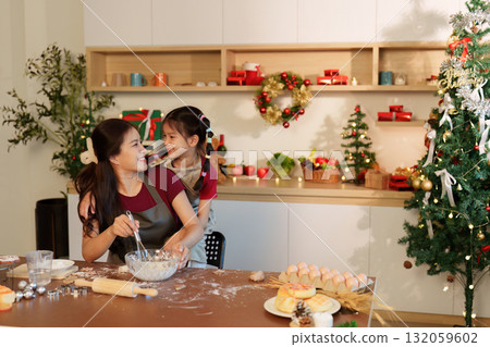 Festive baking fun. Mother and daughter enjoying holiday cooking together in decorated kitchen. Festive baking fun. Mother and daughter enjoying holiday cooking together in decorated kitchen. 132059602