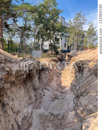 Eroded Sandy Trench Near Modern Building 132060580